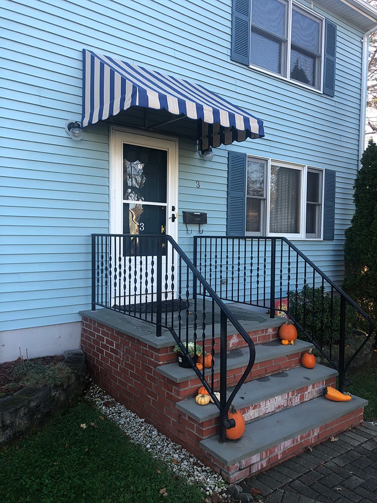 striped door canopy installed on blue house