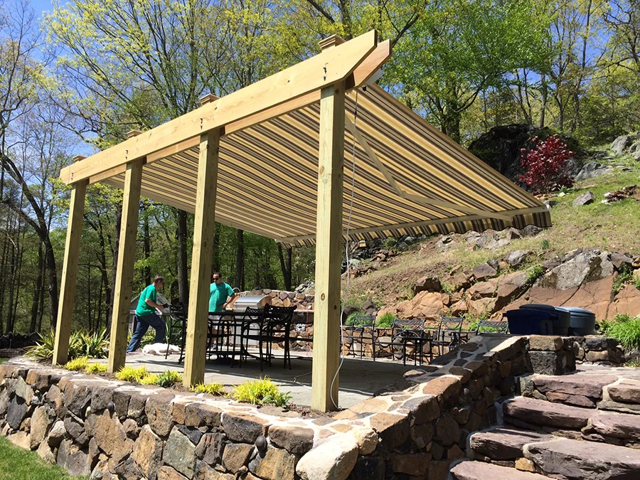 outdoor cooking area covered with pergola containing a retractable awning