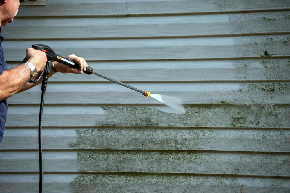 older gentleman power washing dirty vinyl siding