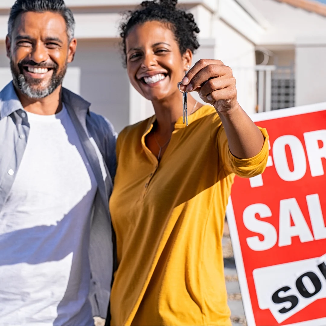 man and woman in front of new home holding their keys