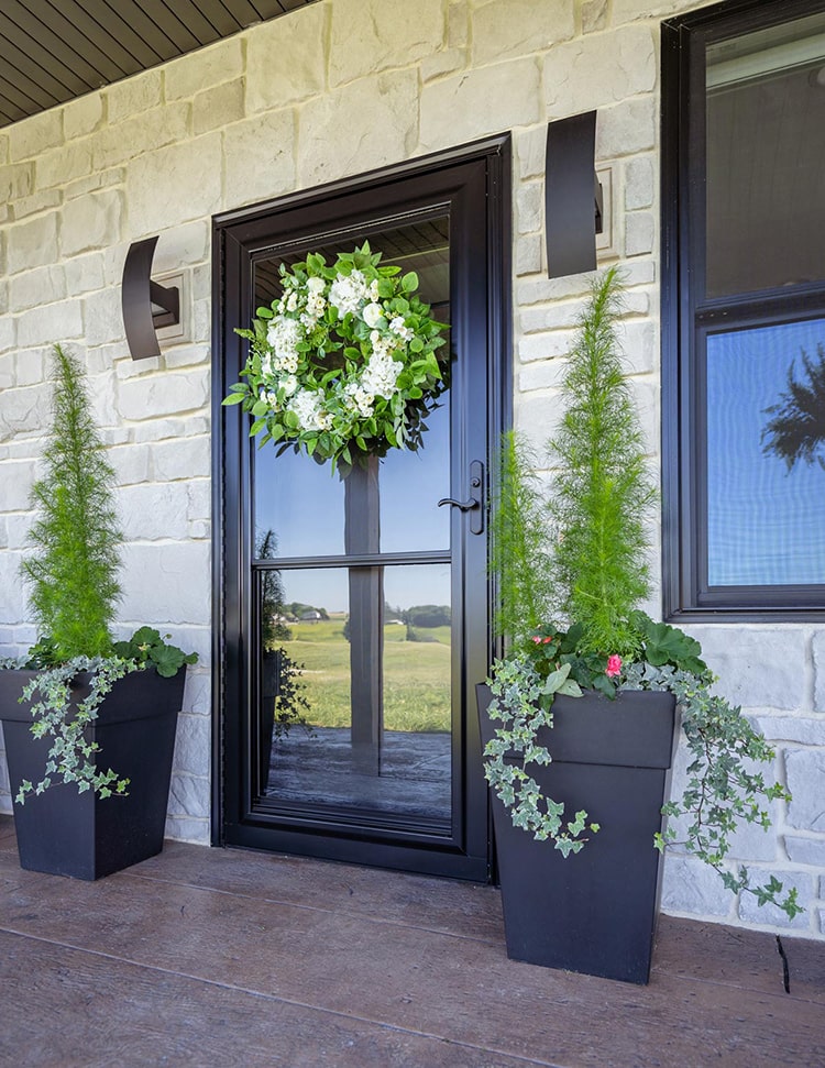 brown storm door with a wreath on it on a tan house