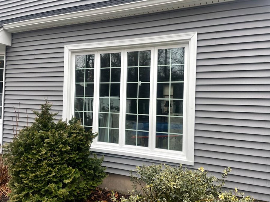 white vinyl replacement window installed on a gray house