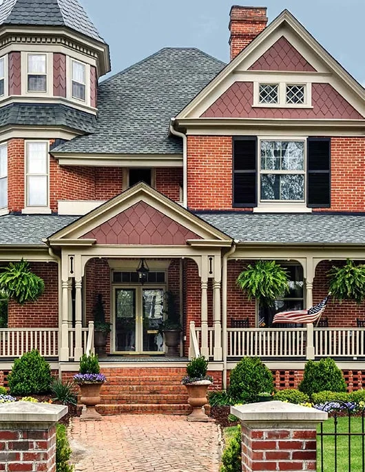 Victorian brick house with a large porch and lots of windows