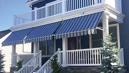 blue fabric window awning with white stripes covering a large porch