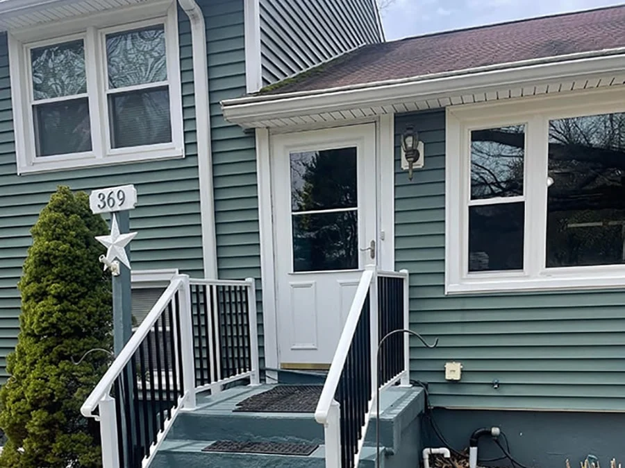 storm door installed on a green house with white trim