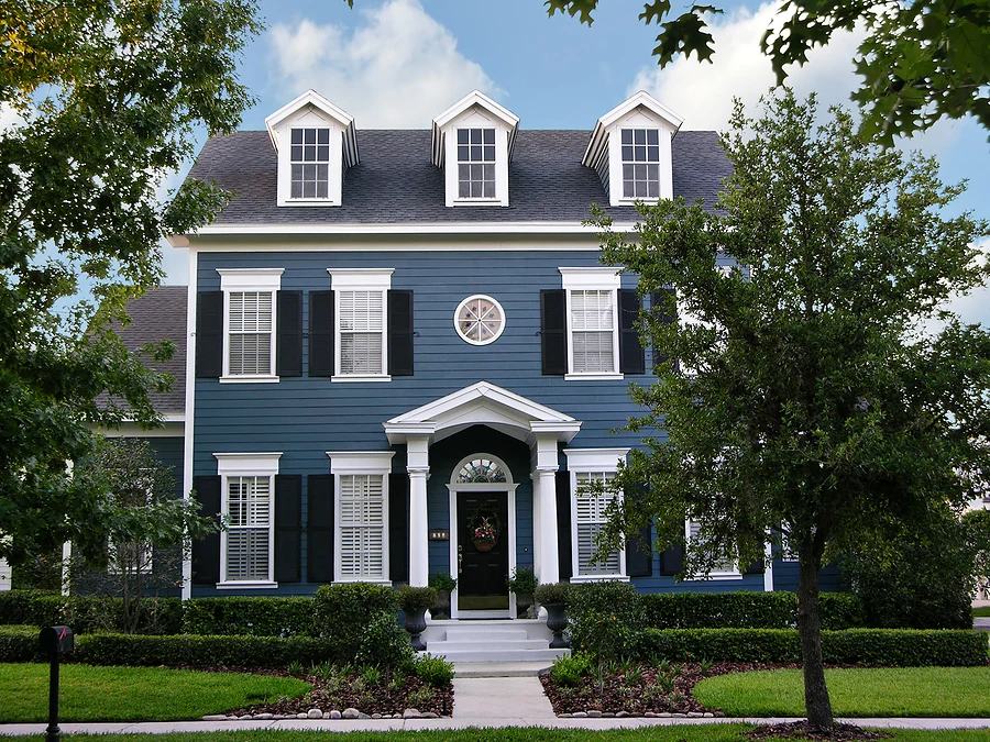 blue three-story colonial style home with black window shutters