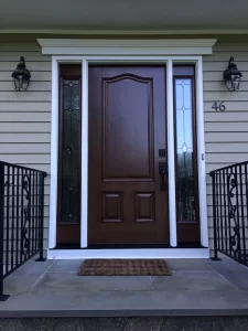 large dark wood entry door with glass side panels