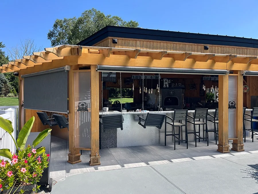 wood pergola with a orange retractable awning beside a pool