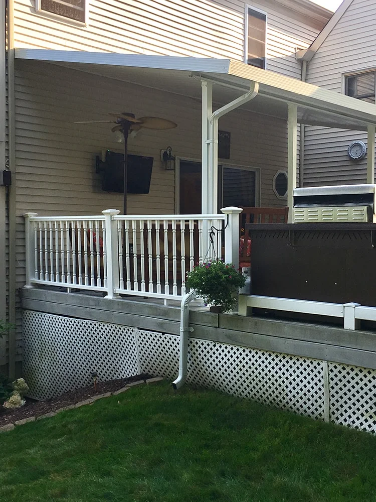 stationary patio cover above a deck with wood railing and a grill