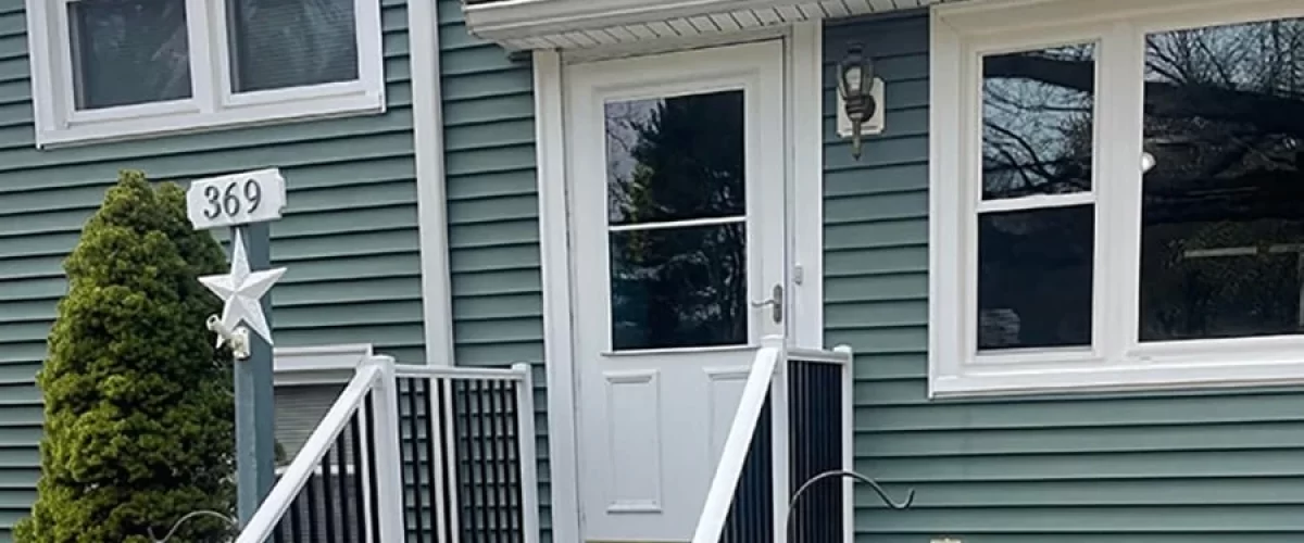 storm door installed on a green house with white trim