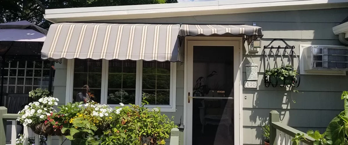 brown striped fabric awning covering a set of windows and the entry door