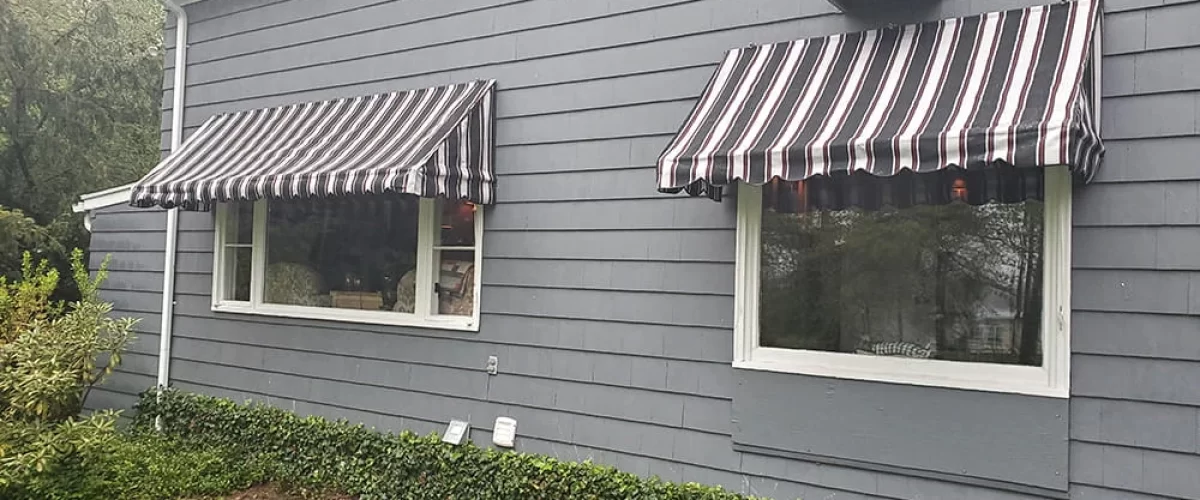 red fabric window awnings with white stripes covering two large windows