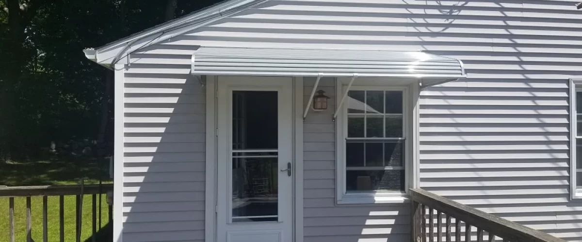 white aluminum door and window canopy above an entry door and small window