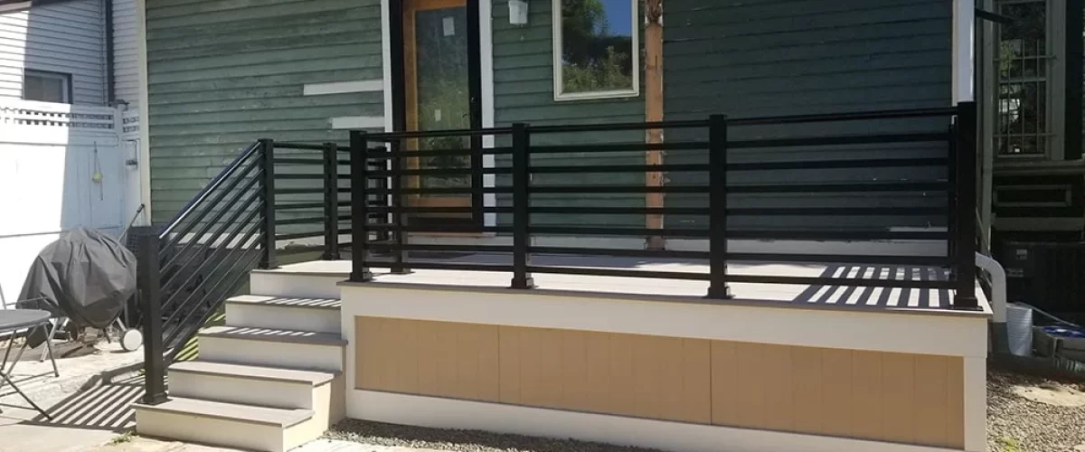 black metal railing on front porch of a green and tan home