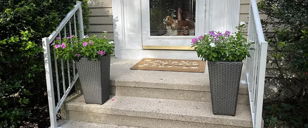 white aluminum railings on a tan house with planters on the stairs