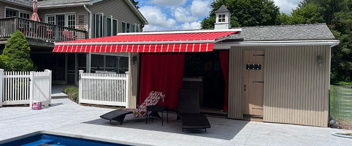 red retractable awning with white stripes on the pool house