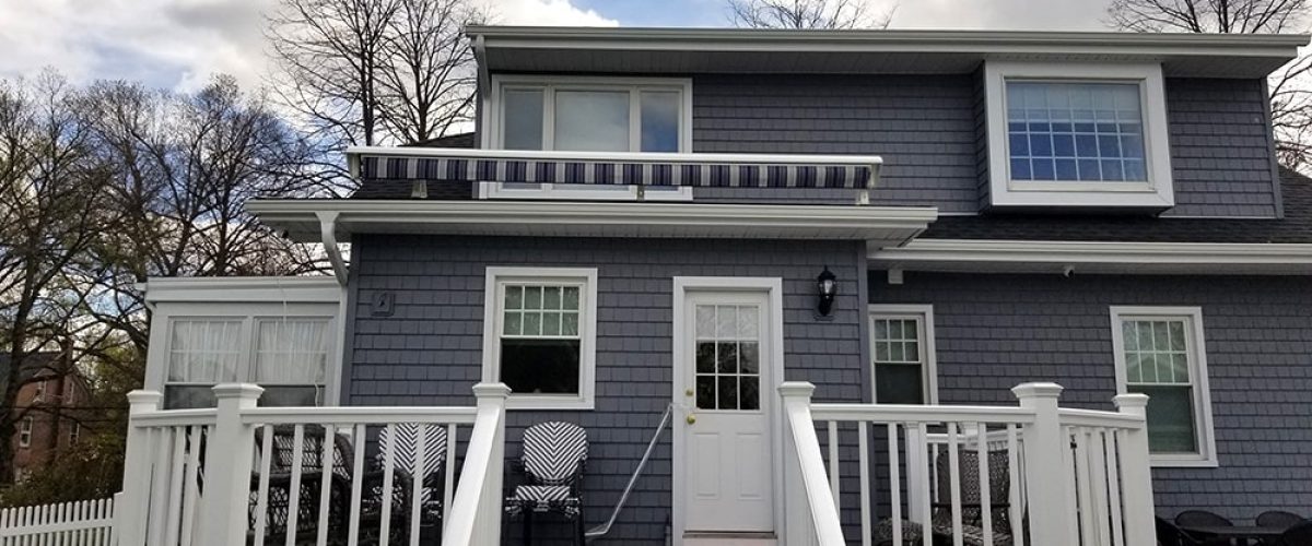 blue and white striped retractable awning installed above porch