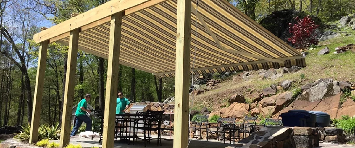 outdoor cooking area covered with pergola containing a retractable awning