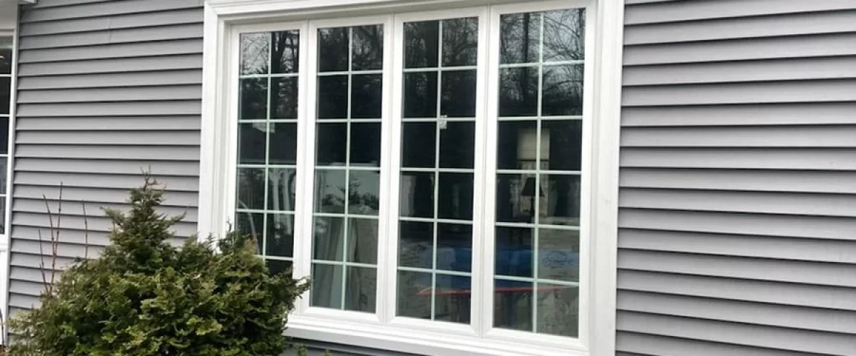 white vinyl replacement window installed on a gray house